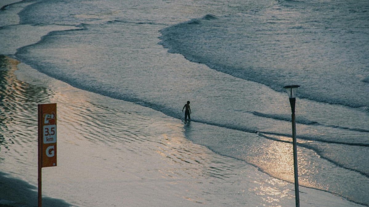 A lone person walks by the ocean at sunset, reflecting peaceful solitude.
