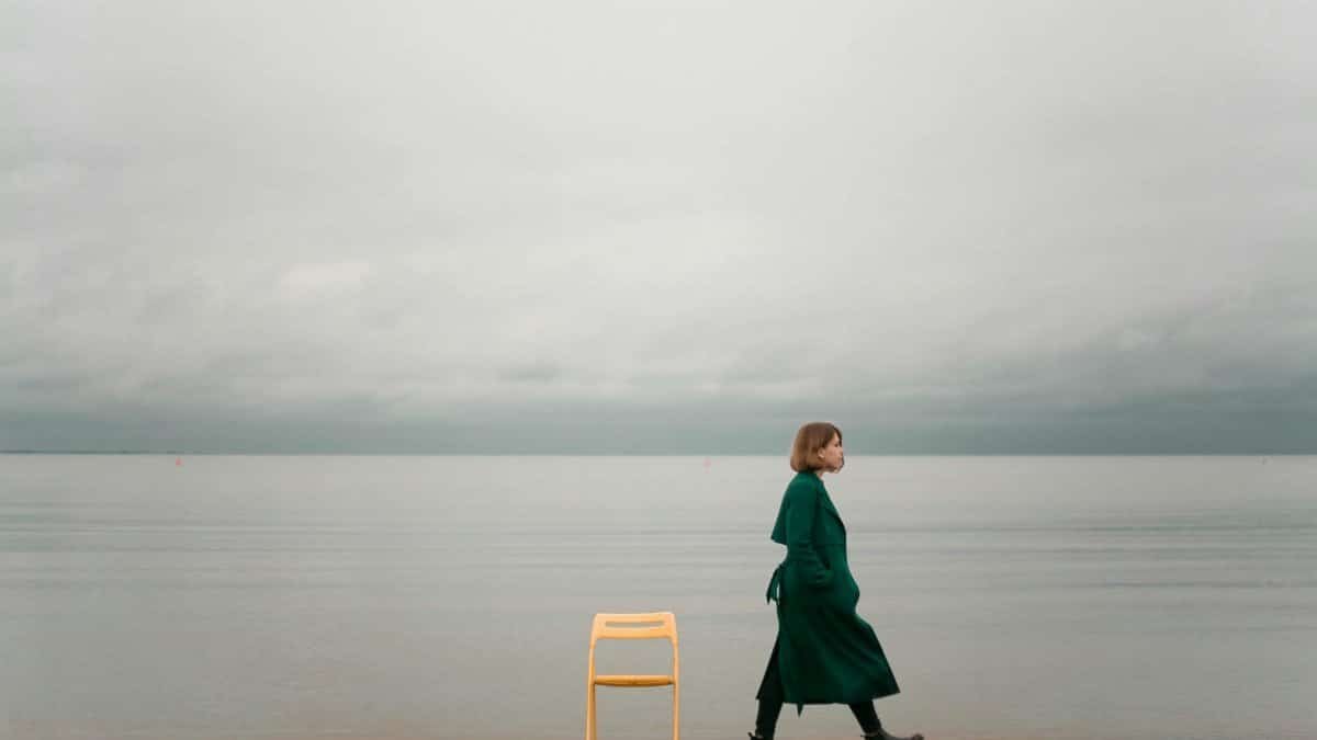 A solitary woman walks by the ocean, capturing calm and introspective solitude.