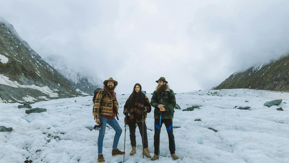 Three friends enjoying a winter hike on a snowy mountain glacier, surrounded by breathtaking nature.