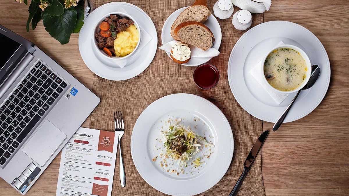 An overhead shot of a meal setup with laptop, showcasing food and productivity in a cozy indoor setting.
