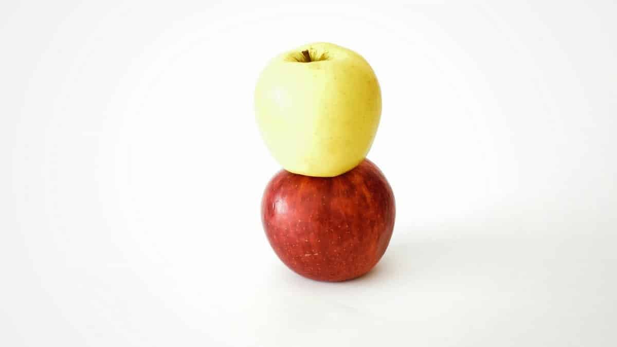 Two apples stacked on a white surface, showcasing balance and simplicity.