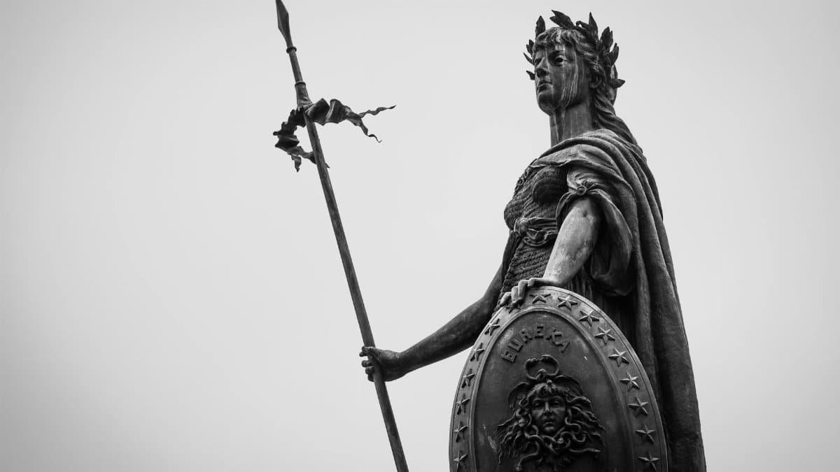A monochrome photograph showcasing a classic statue holding a spear and shield, exuding timeless strength.