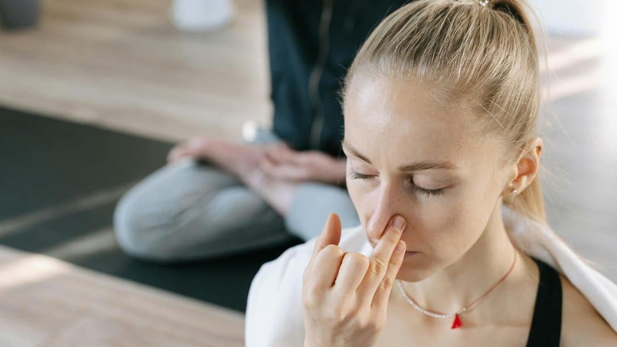 Woman meditating indoors practicing yoga breathing techniques with focused concentration.