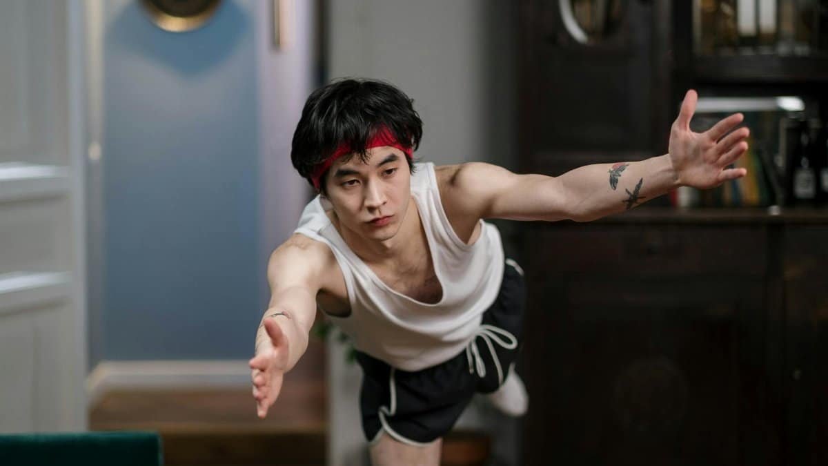 Asian man practicing yoga indoors, focusing on balance and healthy lifestyle during a home workout.