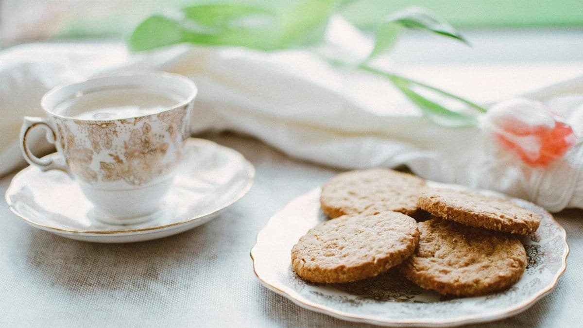 Elegant teacup with biscuits on a plate, perfect for a cozy afternoon snack.