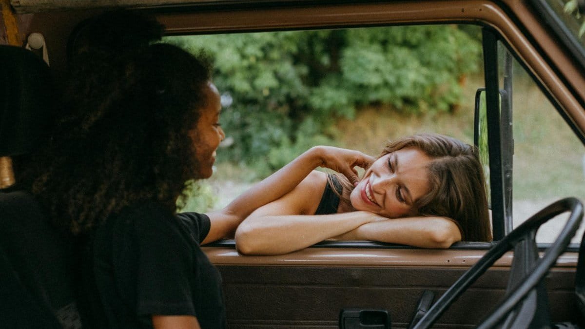 Two friends enjoying a carefree time together in a camper van during a summer road trip.