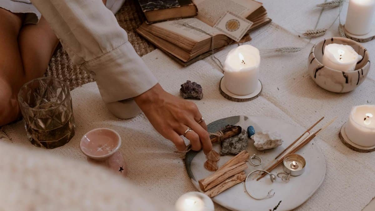 A peaceful ritual scene with candles, crystals, and incense sticks on a wooden table.