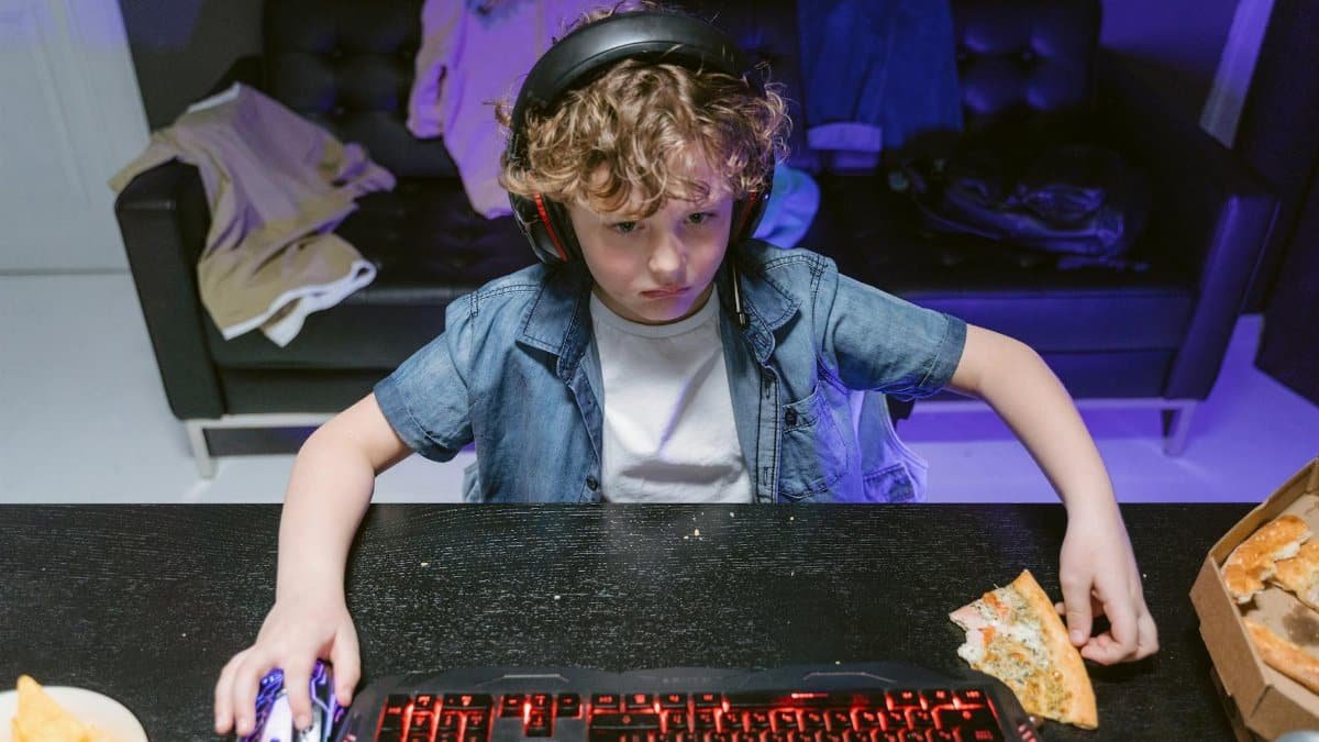 A focused young gamer engages in a nighttime gaming session with snacks and a headset.