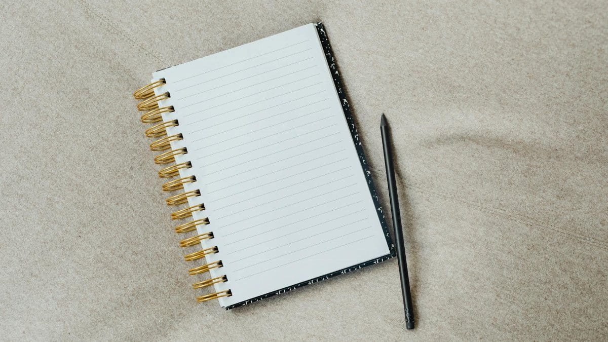 A minimalist notebook with a pencil on fabric surface, ideal for writing themes.