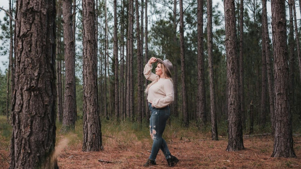 Caucasian woman in a hat walking through a fall forest in Orlando, Florida.