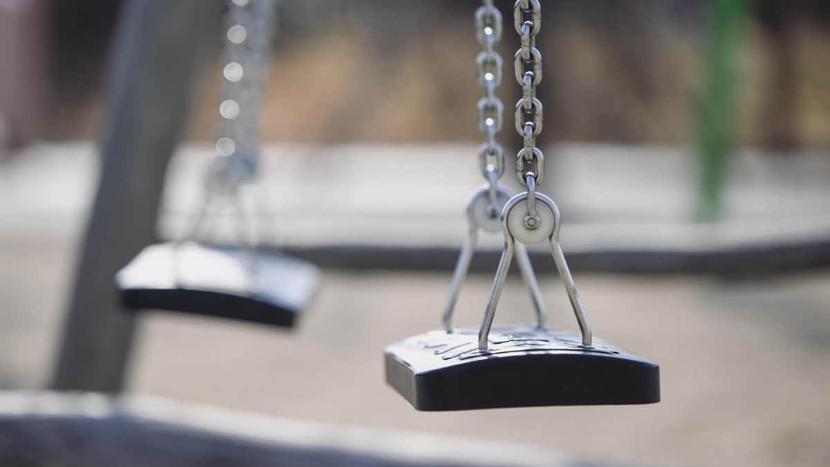 Close-up image of empty swings hanging, evoking a nostalgic and tranquil mood.