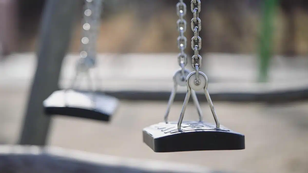 Close-up image of empty swings hanging, evoking a nostalgic and tranquil mood.