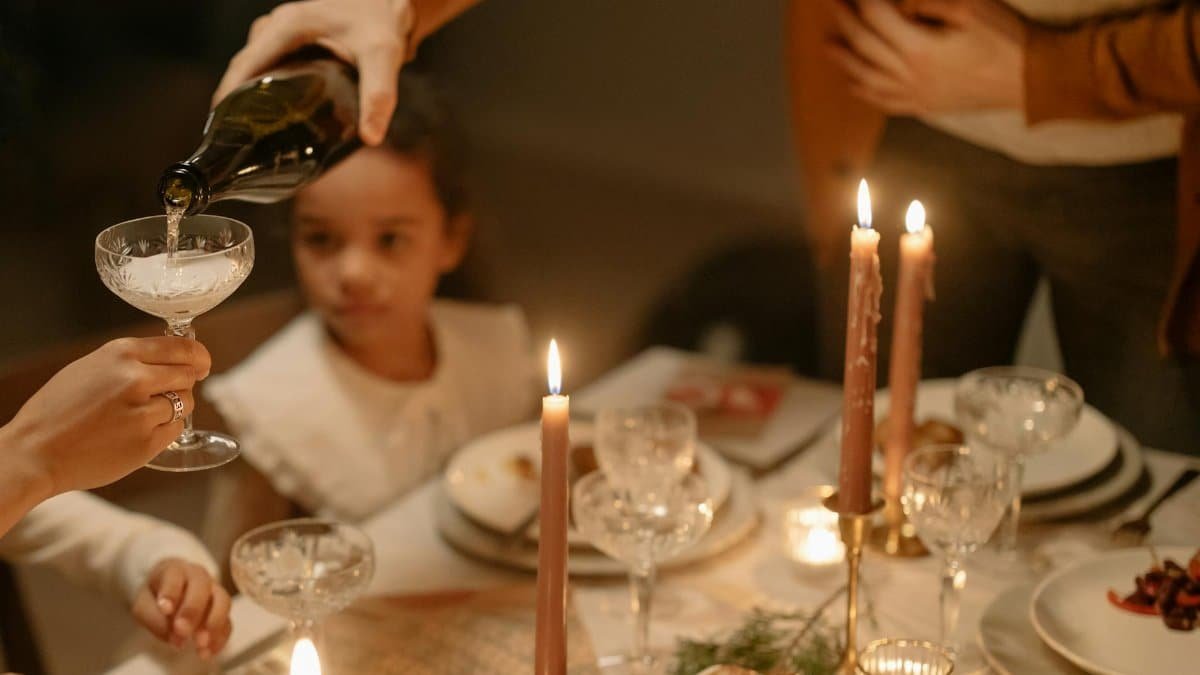 A warm family dinner scene with candles, wine, and a child present at the table.