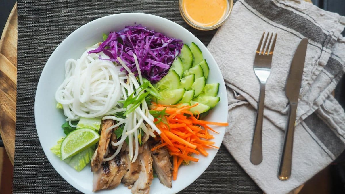 Vibrant Vietnamese noodle bowl with chicken, fresh vegetables, and spicy dressing.