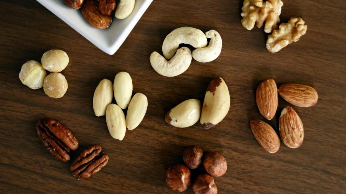 Close-up of various nuts on a wooden table, showcasing healthy snacking options.