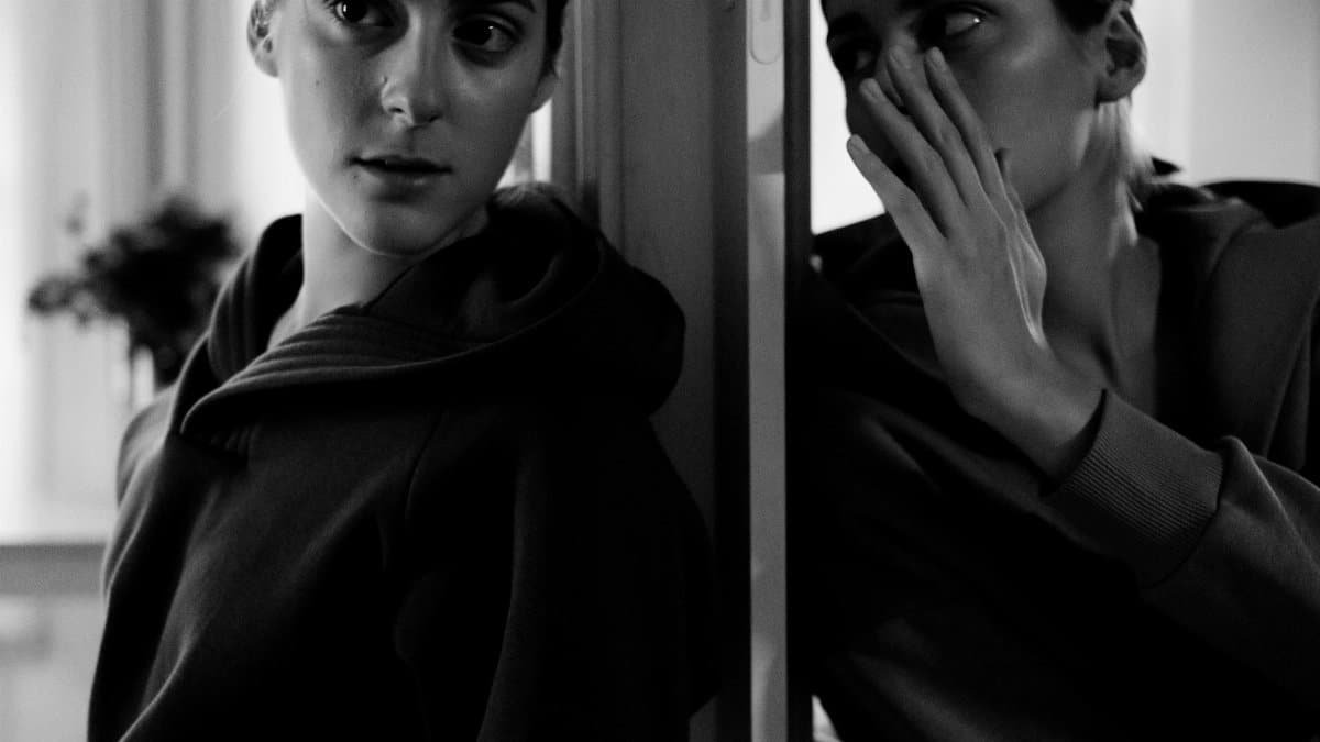Black and white portrait of a woman in deep thought, whispering to her reflection.