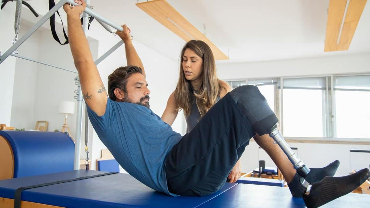 Man with prosthetic leg doing a workout with trainer in a gym, focusing on strength and recovery.