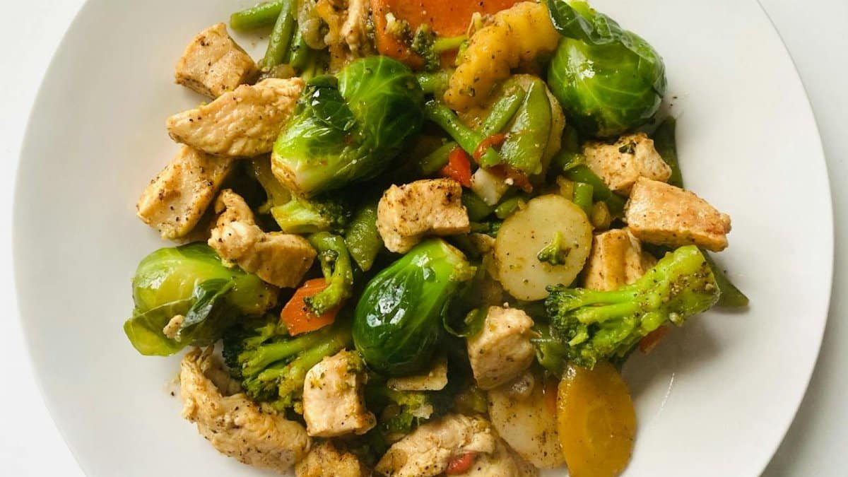 Delicious stir-fry of chicken and vegetables on a white plate for a healthy meal.