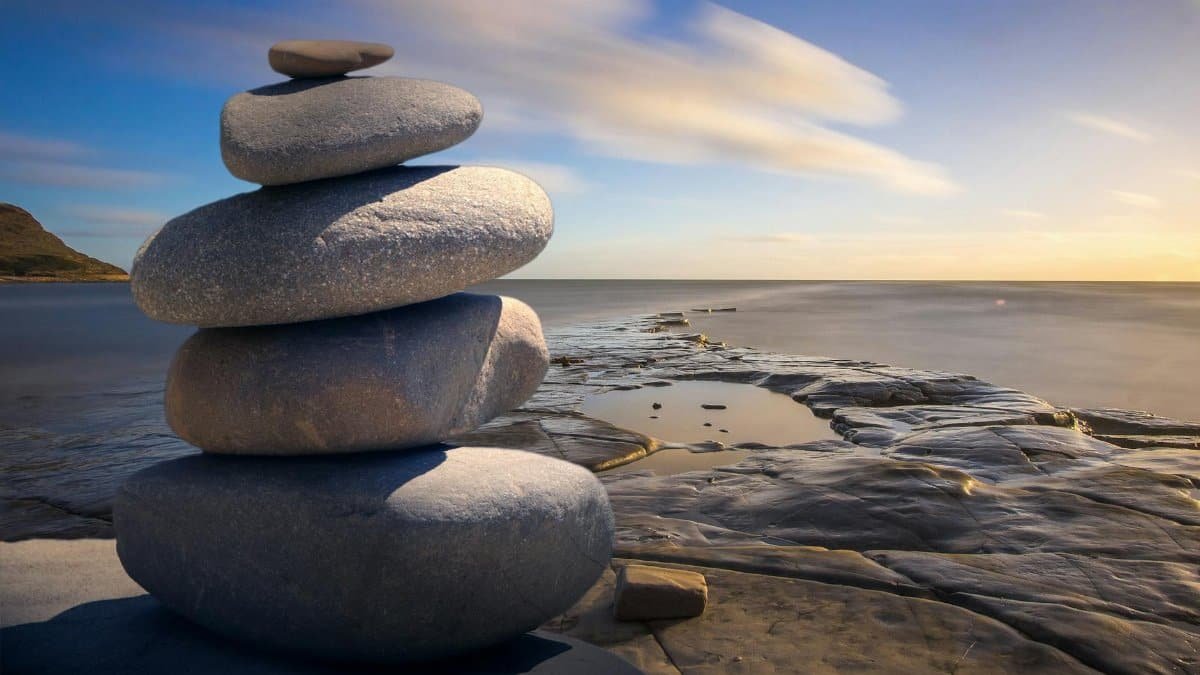 A serene stack of stones on the rocky seashore during a peaceful sunrise, embodying balance and zen.