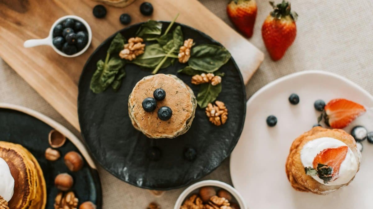 Overhead shot of pancakes with blueberries, strawberries, and walnuts for breakfast.