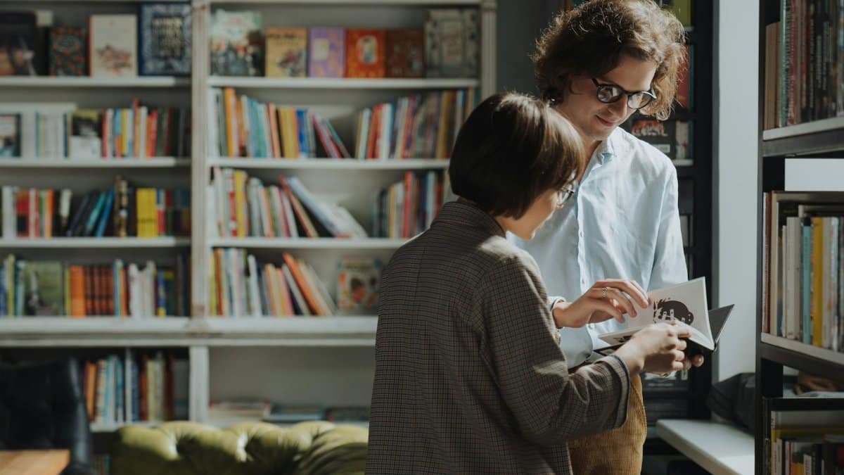 Two individuals engage in a lively book discussion in a cozy library setting.