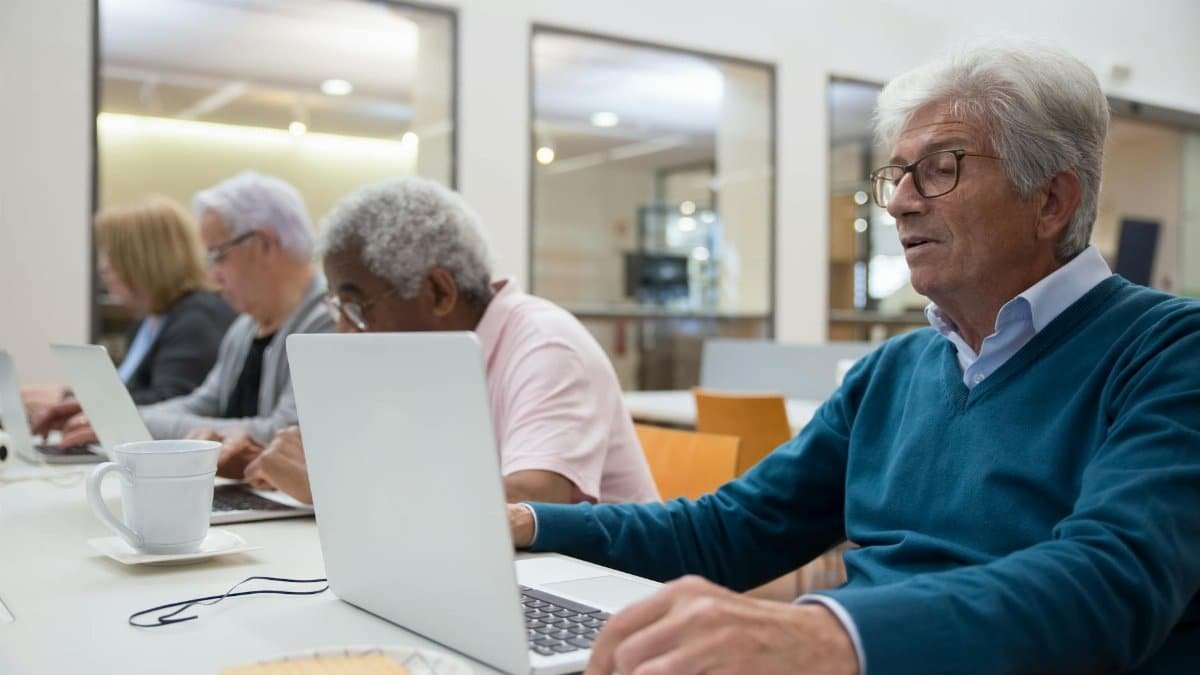 Seniors learning computer skills in a classroom setting, enhancing technology understanding.