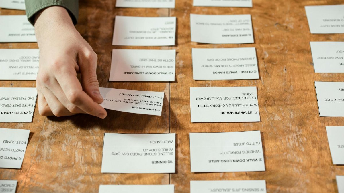 A person arranges cards with various texts on a wooden table, emphasizing focus.