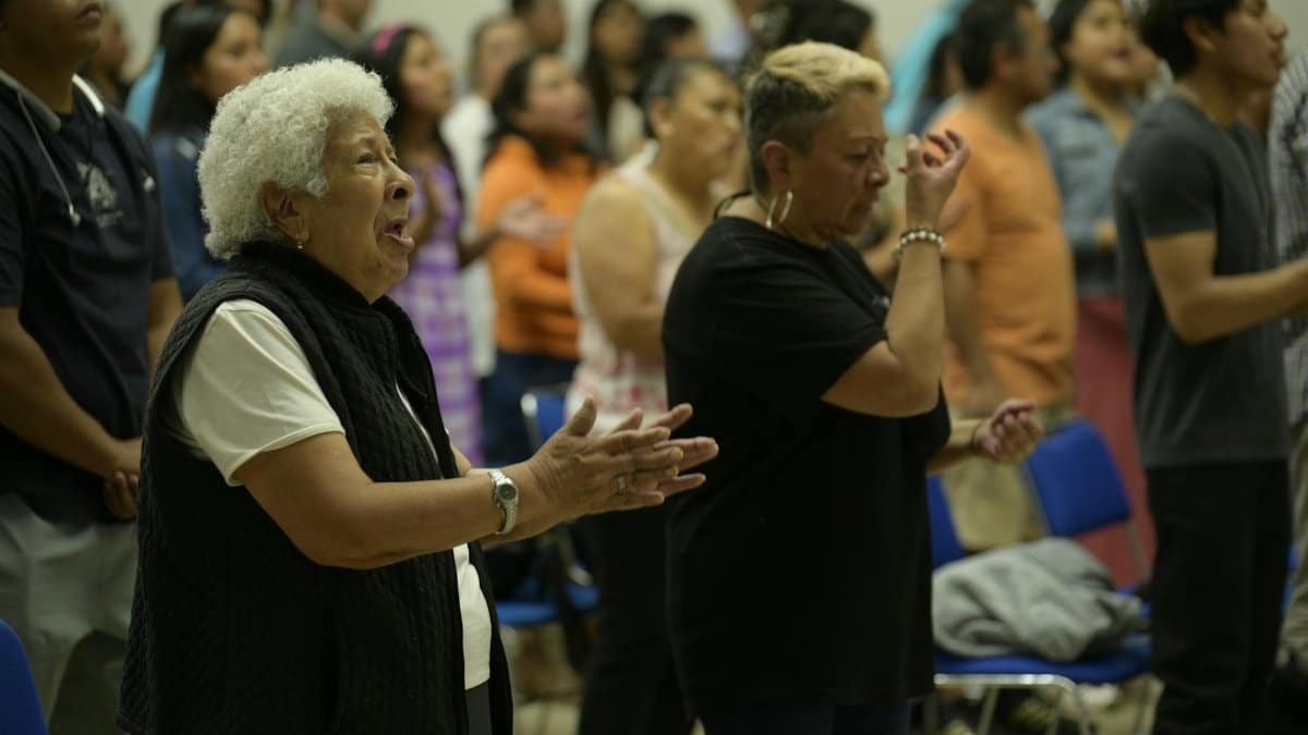 People gathered in a church in Ciudad de México, participating in a community worship service with singing and praying.