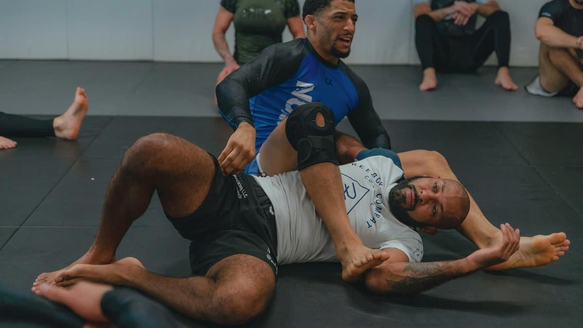 Two men engaged in a grappling training session at a martial arts gym, showcasing technique and focus.