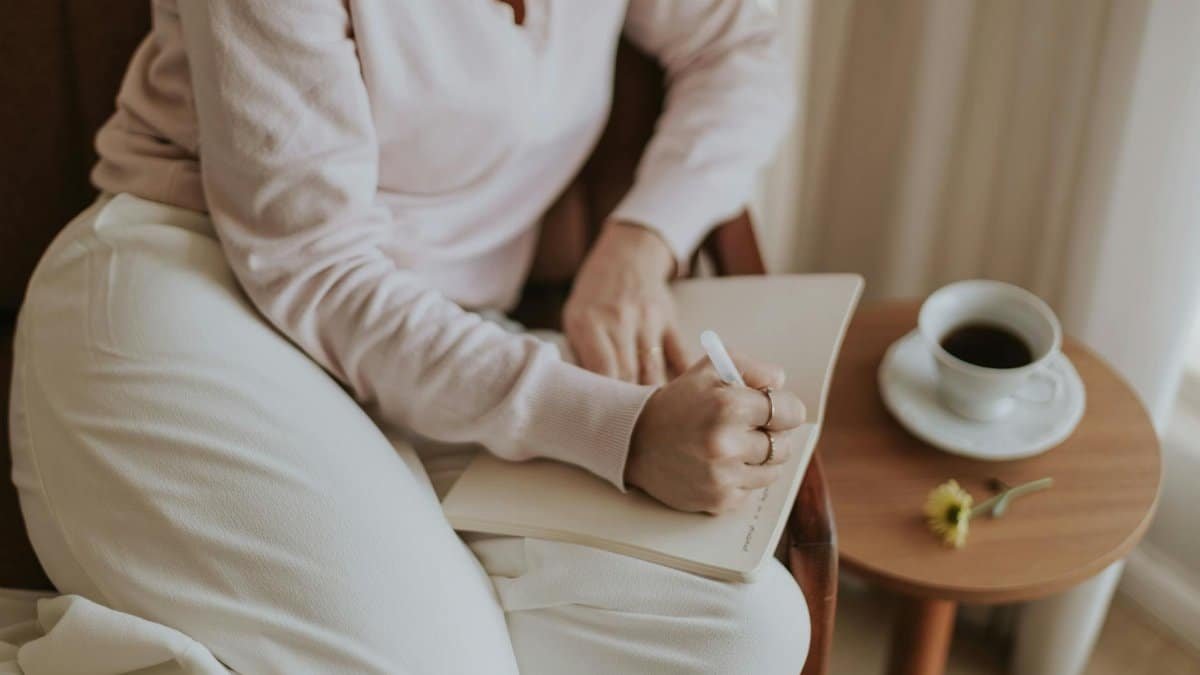 A person journaling in a cozy room with a cup of coffee. Warm and inviting atmosphere.
