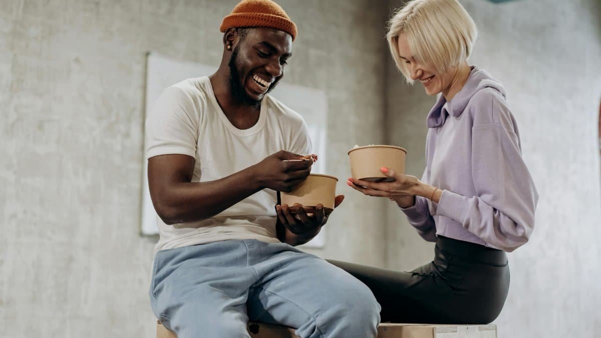 Two friends sharing a joyful moment while enjoying a healthy meal indoors.
