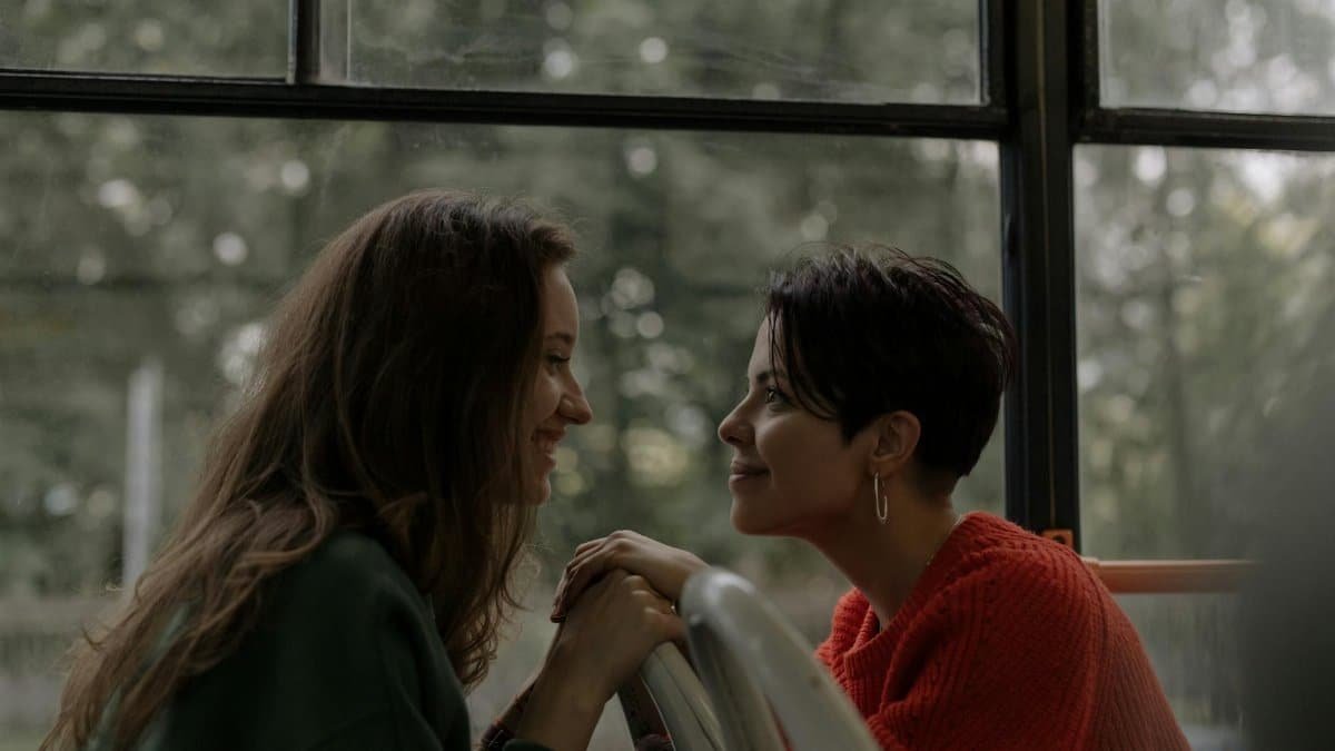 Two women share a heartfelt moment on a bus, showcasing love and connection.