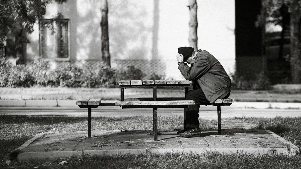 A senior man in solitude, deep in thought, sitting at a park bench in Eskişehir.
