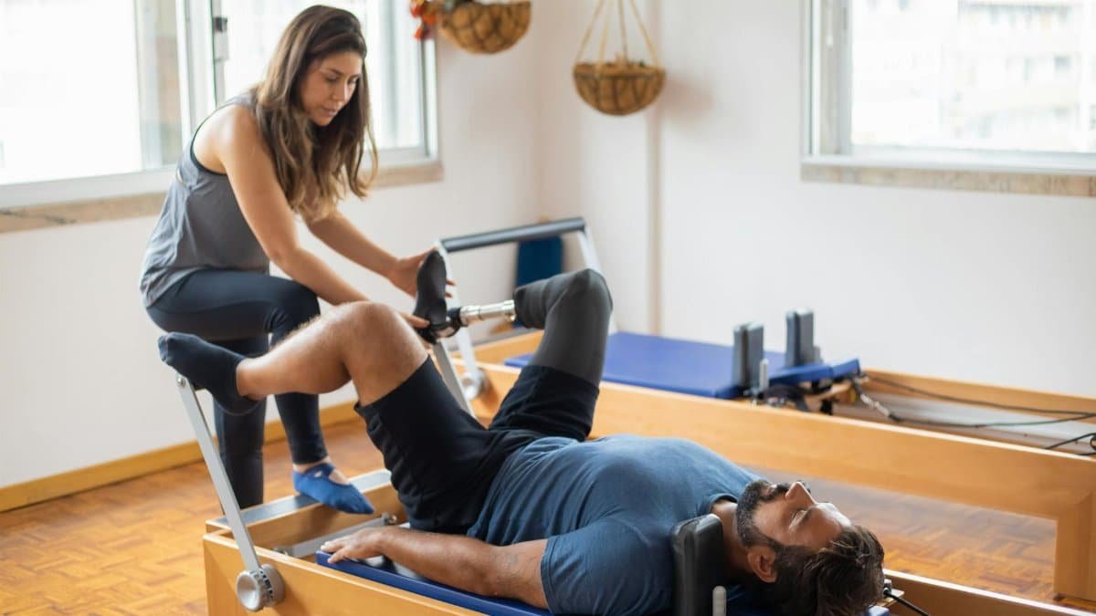 Adaptive pilates session with prosthetic leg focus on recovery and fitness indoors.