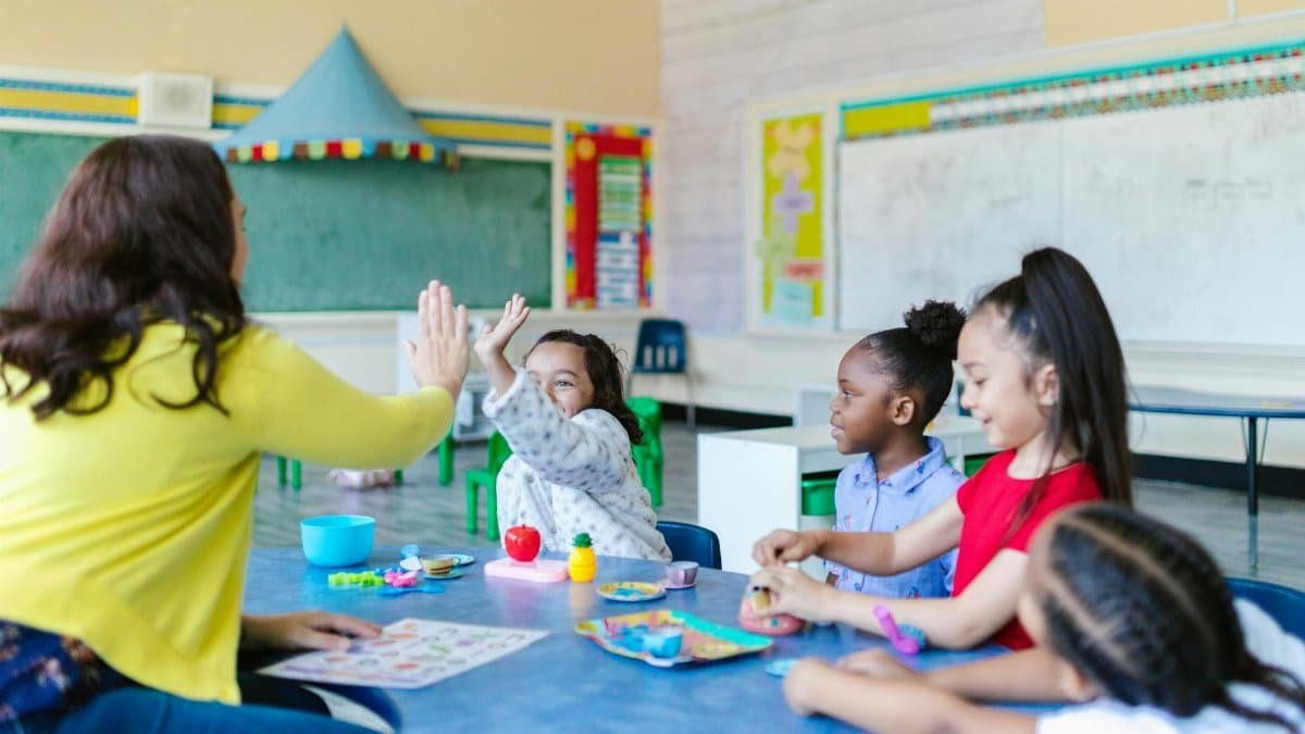A joyful classroom scene with a teacher and diverse group of children engaging in playful learning activities.
