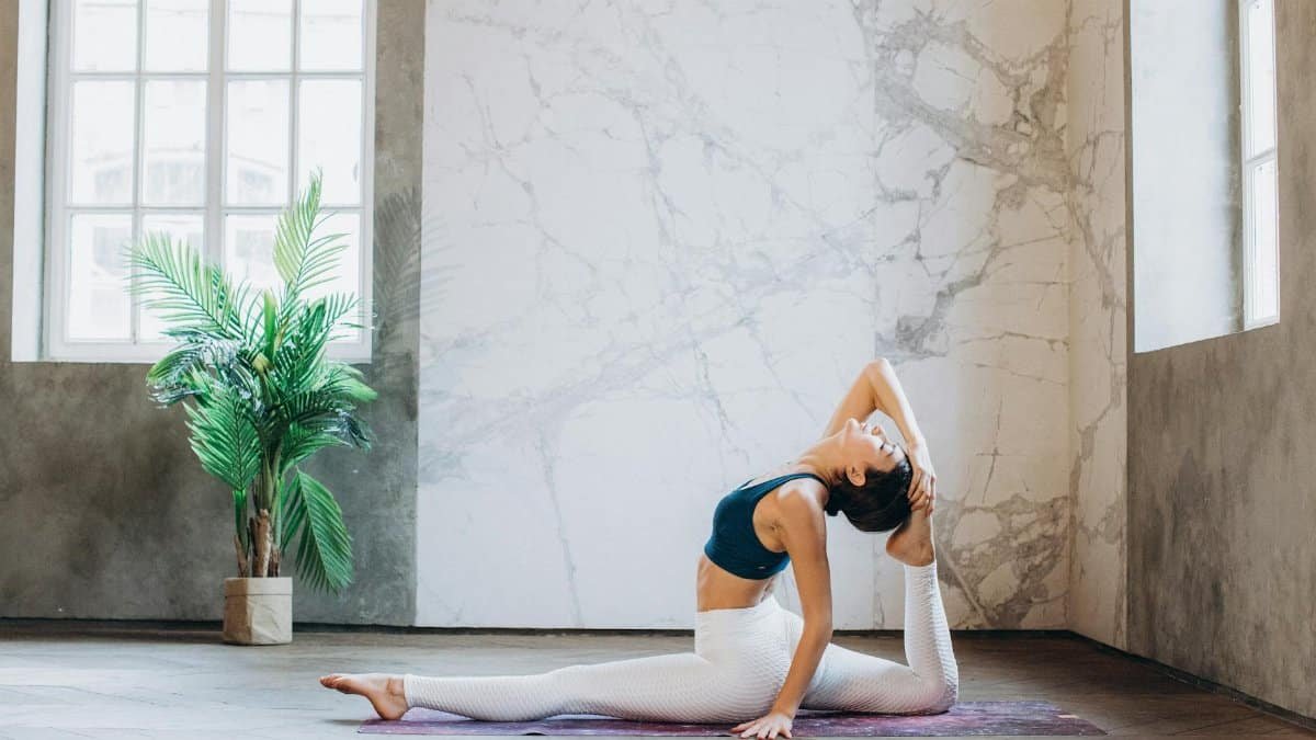 Woman doing yoga in Hanumanasana pose indoors, focusing on mindfulness and flexibility.