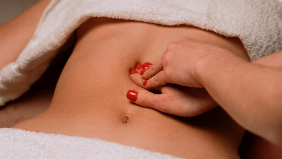 A soothing massage on a woman's abdomen with painted nails, creating a serene spa atmosphere.