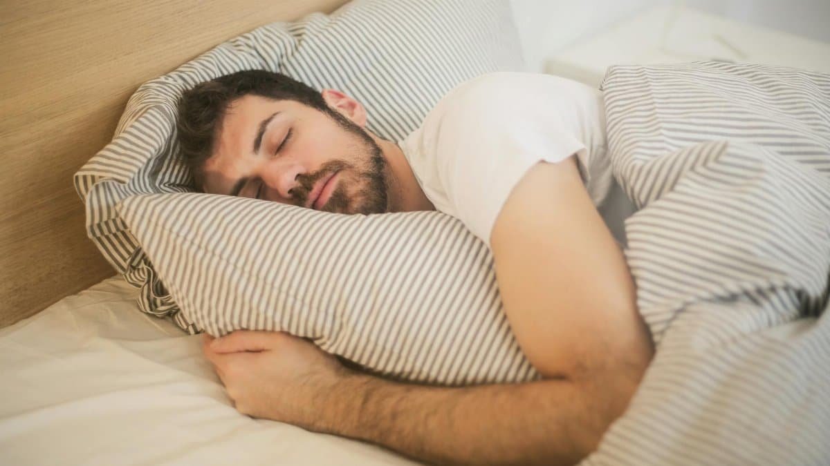 Man sleeping peacefully on striped bedding, embracing relaxation and comfort.