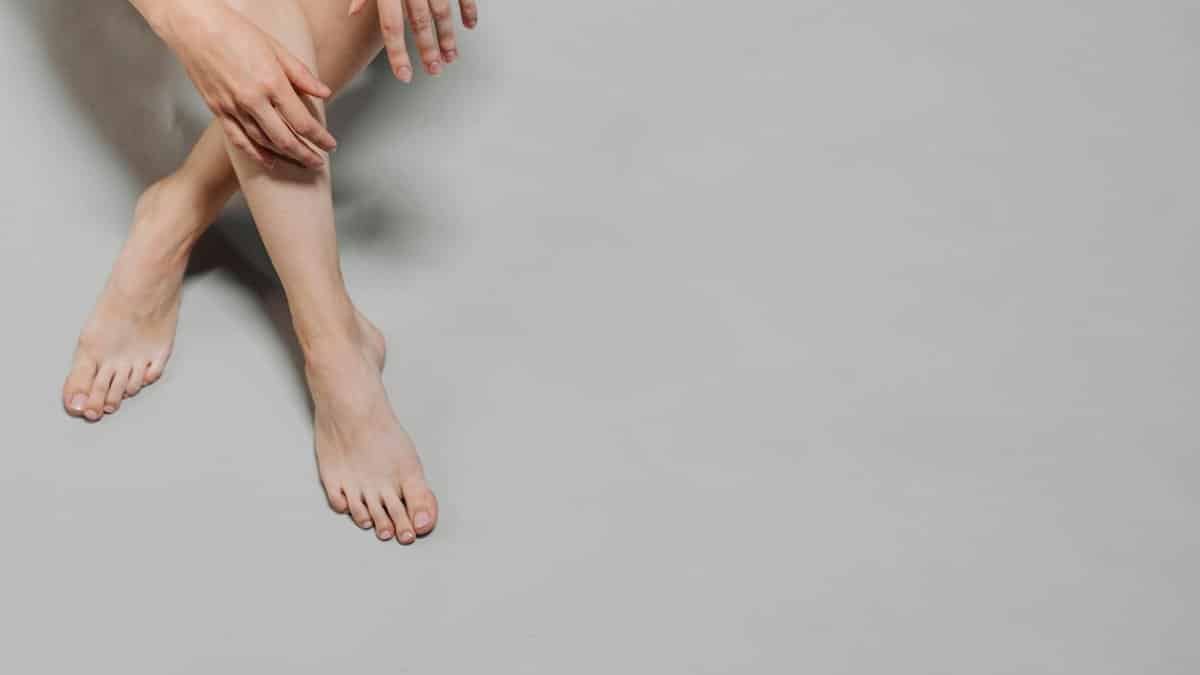 Artistic close-up of crossed legs and hands on a gray background. Ideal for wellness and lifestyle themes.