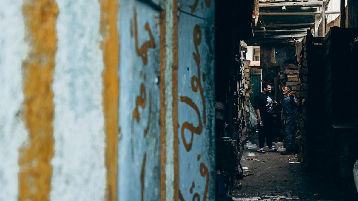 Two men converse in a narrow alleyway in Damietta, Egypt, capturing local street life.
