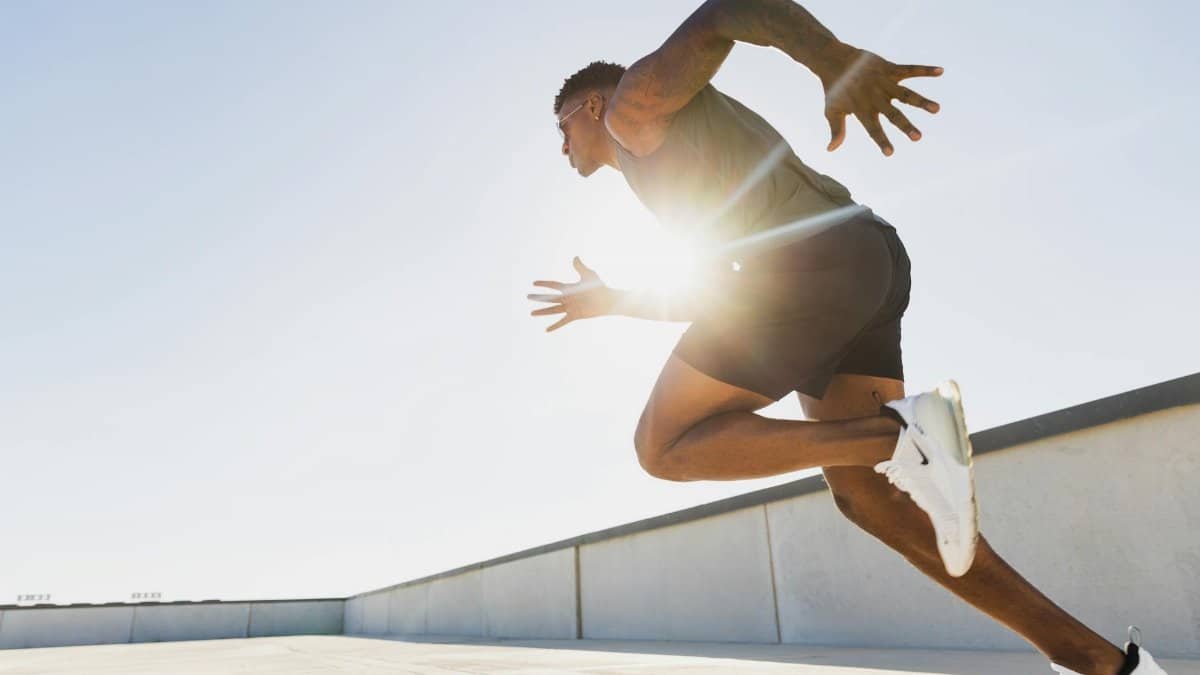 Dynamic side profile of an athletic man sprinting on a rooftop in Austin, Texas at sunrise.