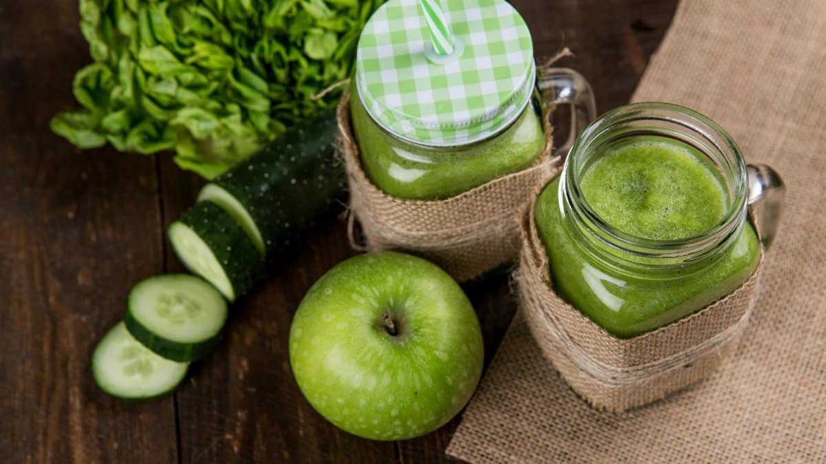Refreshing green smoothie made with apple, cucumber, and lettuce served in mason jars on wooden background.