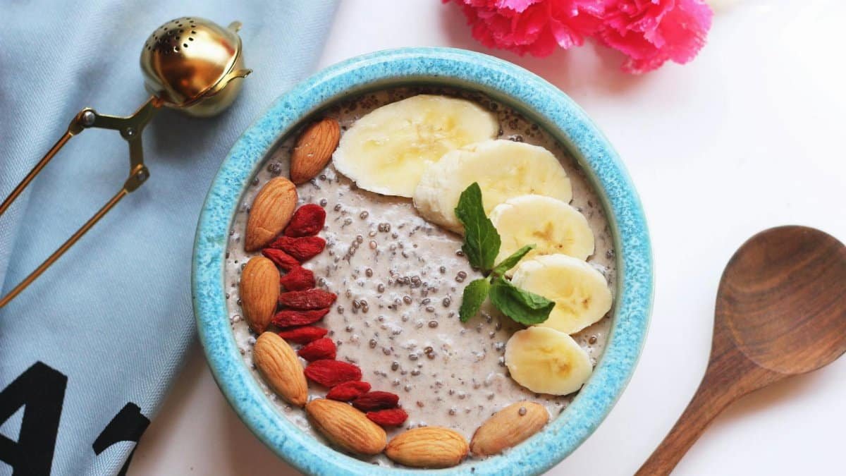 A fresh and delicious chia pudding bowl topped with bananas, almonds, and mint leaves.