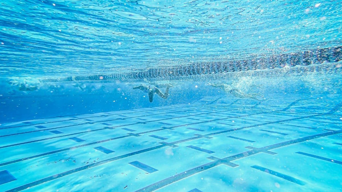 Underwater view of swimmers in a pool, showcasing motion and splash.