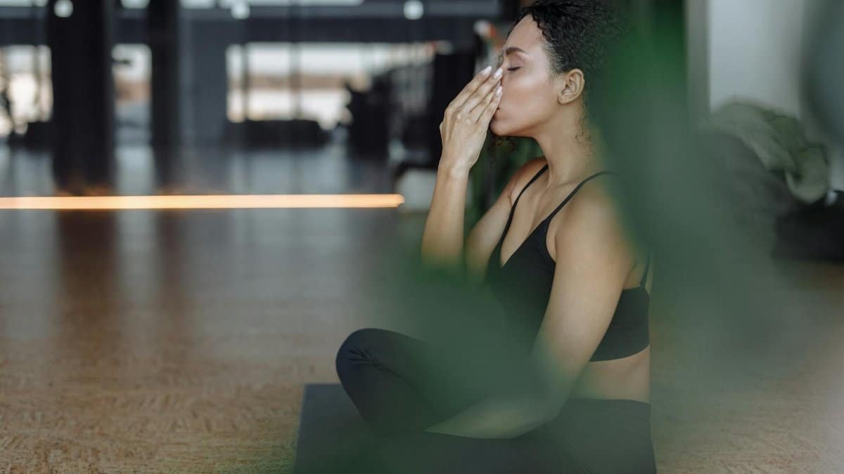 Peaceful woman practicing yoga indoors with eyes closed, focusing on breathing and relaxation.