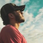 A man enjoys outdoor relaxation and mindfulness beneath a bright, cloudy sky, exuding calm and peace.