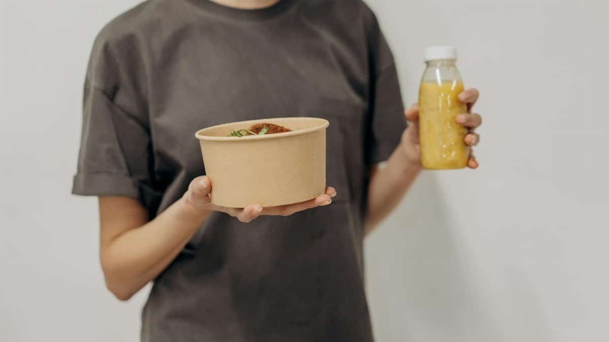 Faceless woman holding a rice bowl and juice bottle, representing healthy lifestyle and nutrition.