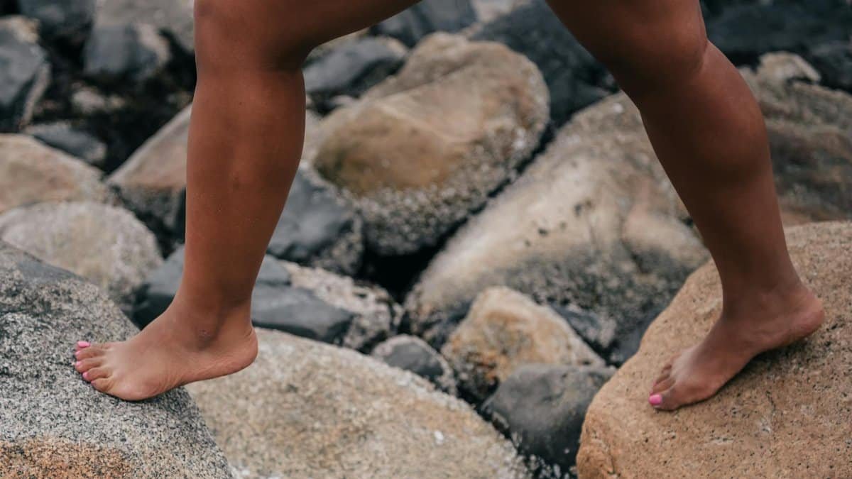 Close-up of a person walking barefoot on rocky terrain, emphasizing natural movement and outdoor exploration.