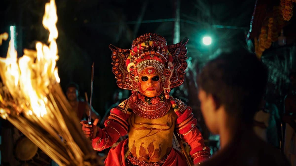 Captivating image of a traditional Theyyam performer with fire in a night festival setting.