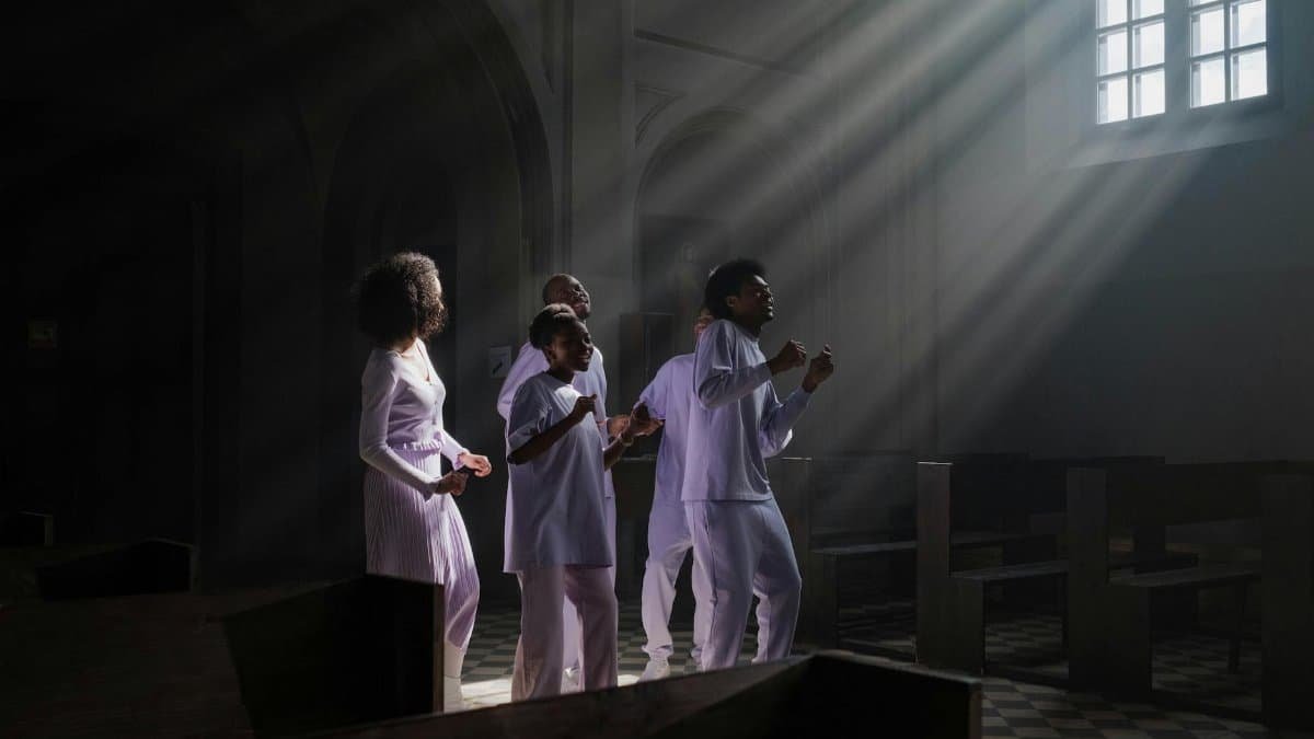A diverse group singing in a church, illuminated by sunrays through a window.